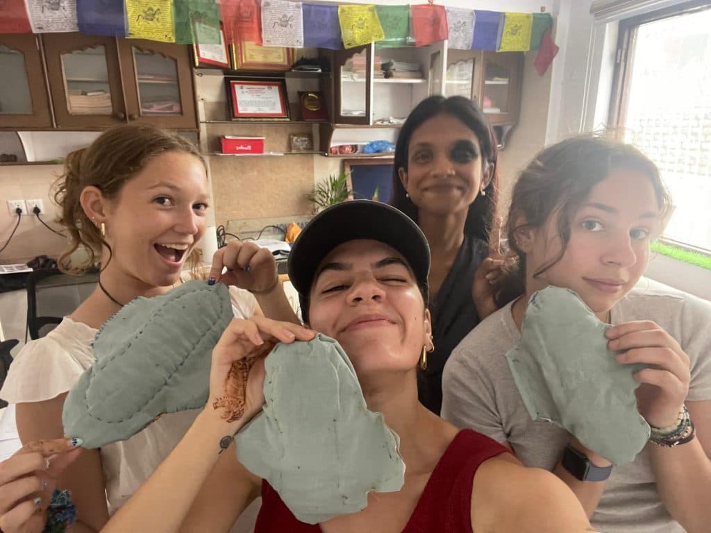 Four people holding up large handmade pad-shaped prototypes in a workshop room