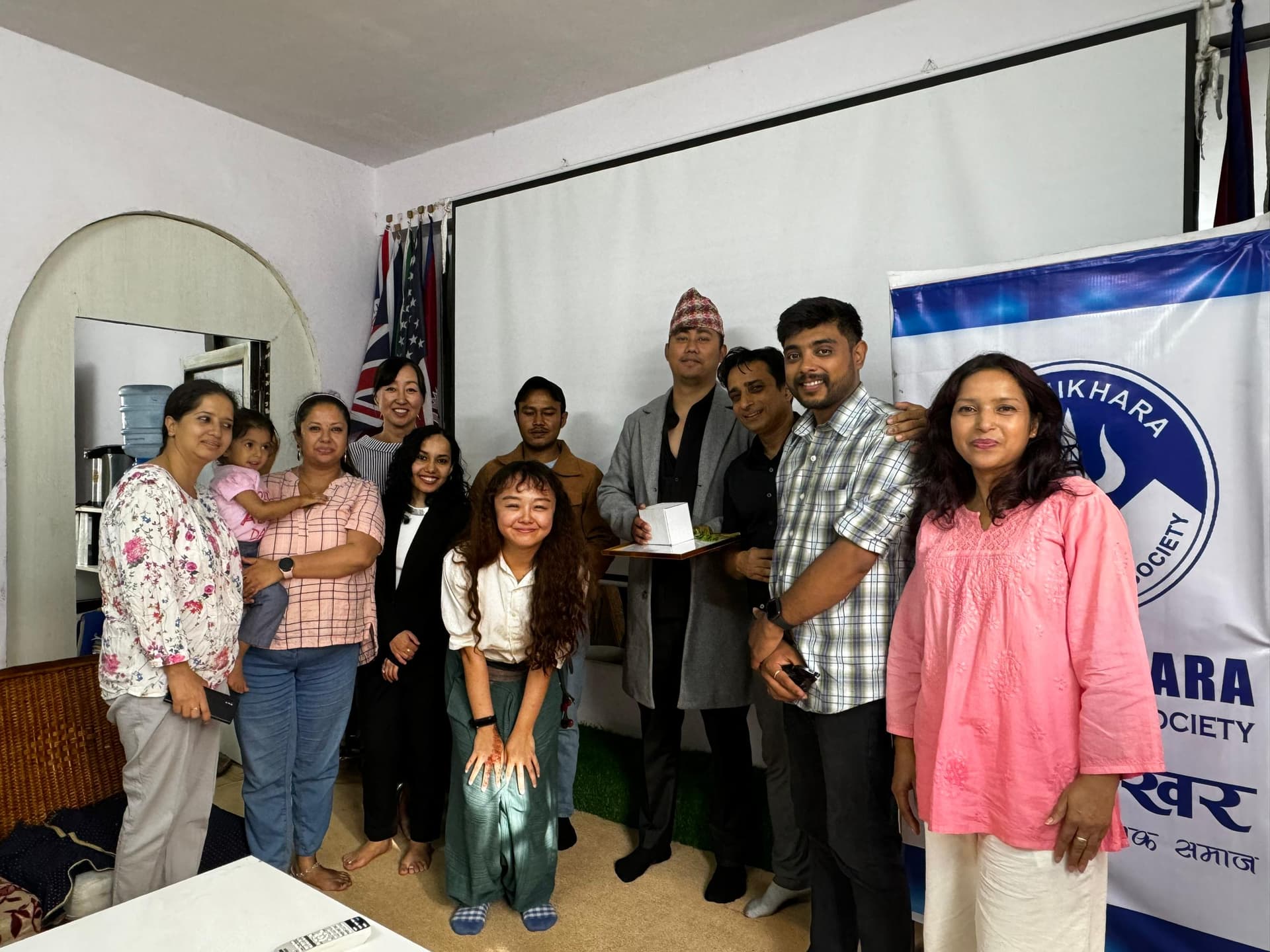 Staff, volunteers and community members gathered for a certificate handover beside an organisation banner