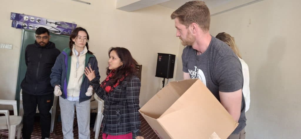 Volunteers and staff carrying and handing over cardboard boxes of supplies indoors