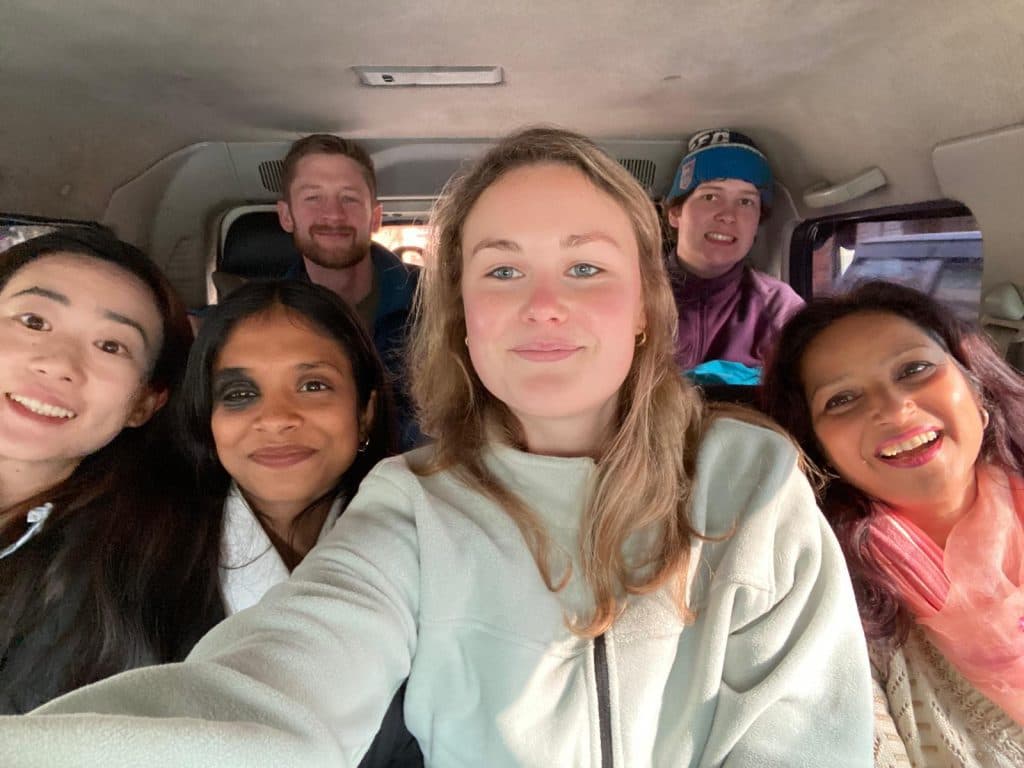 Six volunteers and staff seated together inside a vehicle on the way to a field site
