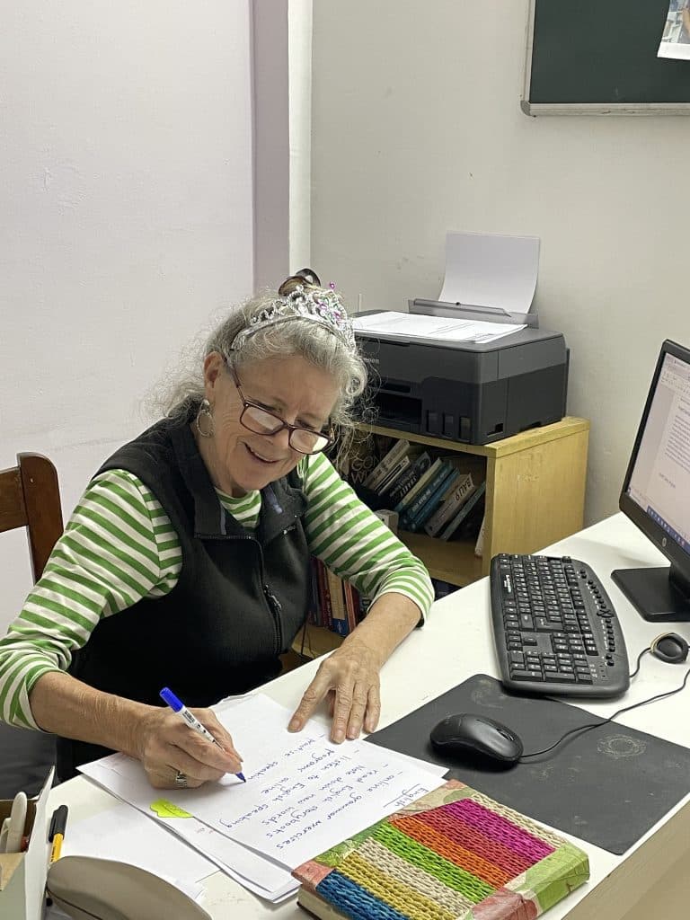 A volunteer writing notes at a desk with a computer and printer in an office
